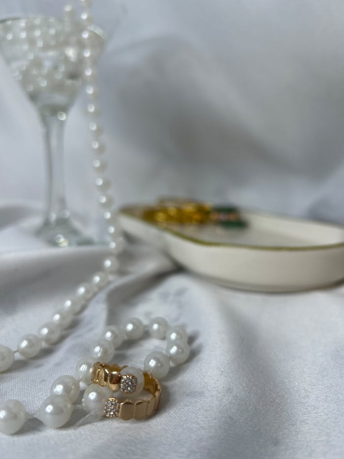 The Art of Drawing Readers In: Your attractive post title goes here Close-up of gold rings and pearl necklace elegantly displayed on white fabric.